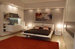 2760 - La camera matrimoniale Stripe è arricchita da dettagli in vera pietra Silver, mentre gli elementi sono laccati opachi Bianco e Tortora; finiture ben combinate tra loro.
La composizione del gruppo letto è elegante ed originale. La forma a 'L' permette una maggior sfruttabilità dello spazio creando un gioco di pieni e vuoti. Pertanto sono ben equilibrati i piani d'appoggio e lo spazio di contenimento.
La pietra è dominante sulla parete a fianco dello specchio ed è ripresa nella fascia centrale dell'armadio scorrevole abbinata ad un'altra fascia laccata Tortora. Stripe