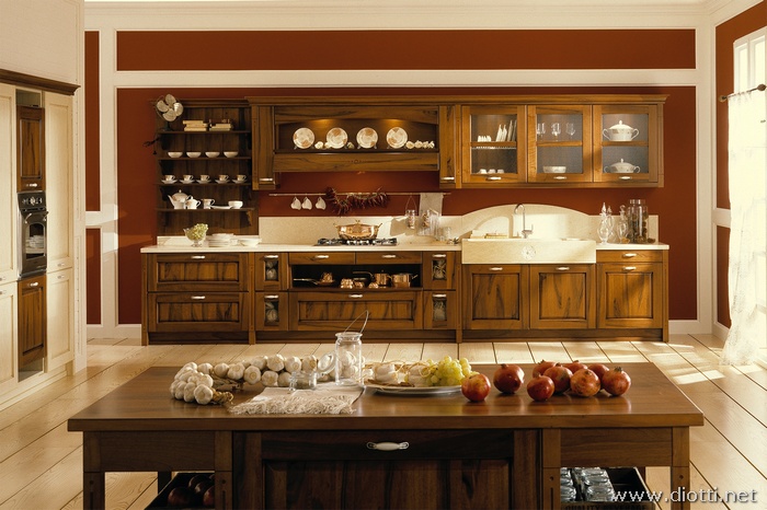 Come cucina classica in legno di noce Dora viene valorizzata sulle ampie metrature, come si vede da questa immagine con la boiserie, l'ampia cappa, il lavello in pietra, l'isola di preparazione...
