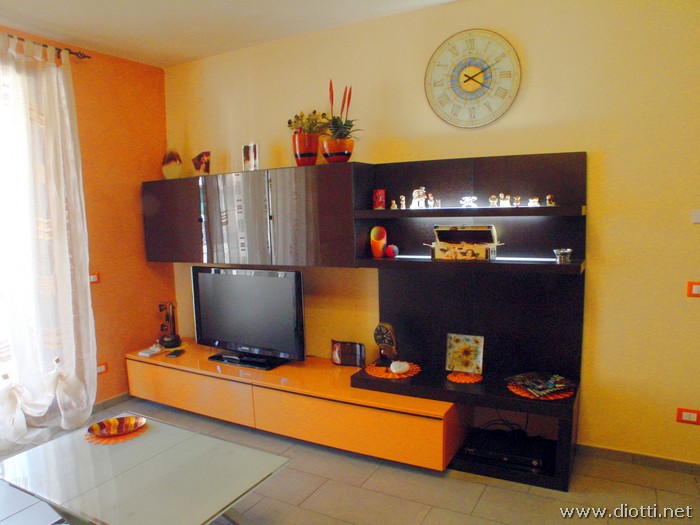 Il soggiorno Day in finitura rovere moro ed arancio lucido.