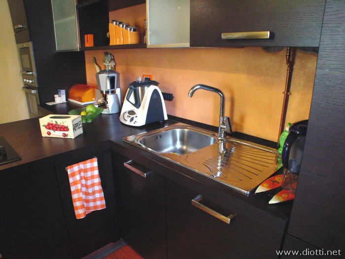 La zona lavello, con il lavabo in acciaio con gocciolatoio e la lavastoviglie (nell'anta di destra), si raccorda alla penisola.