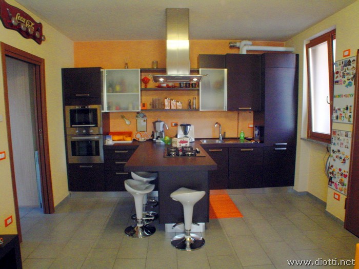 Bella vista frontale della cucina S64 in rovere moro, in particolare vediamo la penisola attrezzata per la cottura.