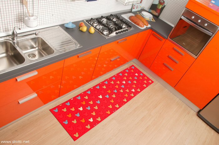 Un classico Disney per una passatoia di fronte a Vela, una cucina Snaidero laccata lucida arancio.